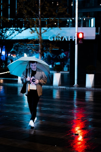 穿黑裤子的女人白天在街上打伞